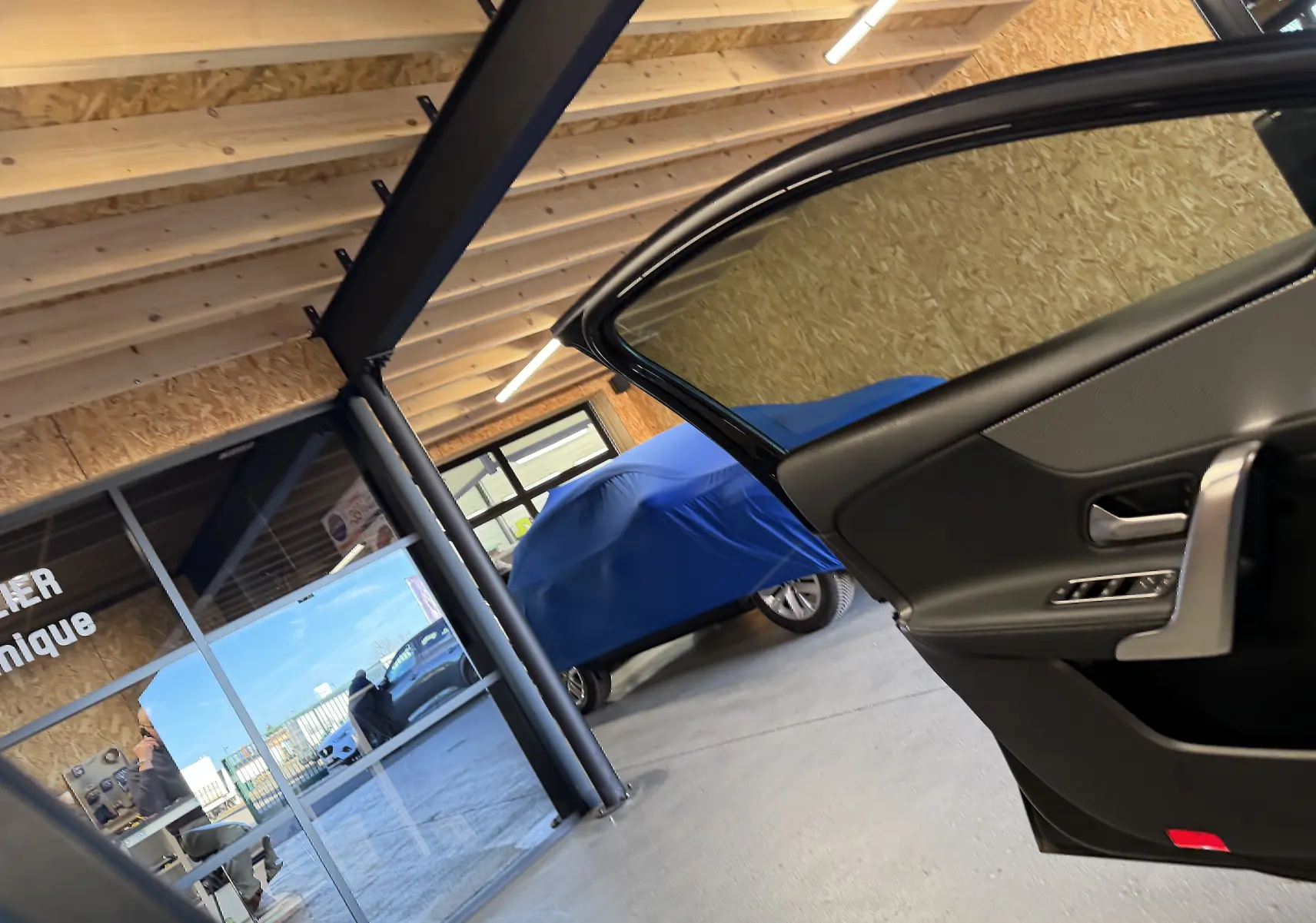 Vue intérieure côté droit de la porte ouverte d'une Mercedes Classe A noire, avec vitres teintées et garniture sombre.