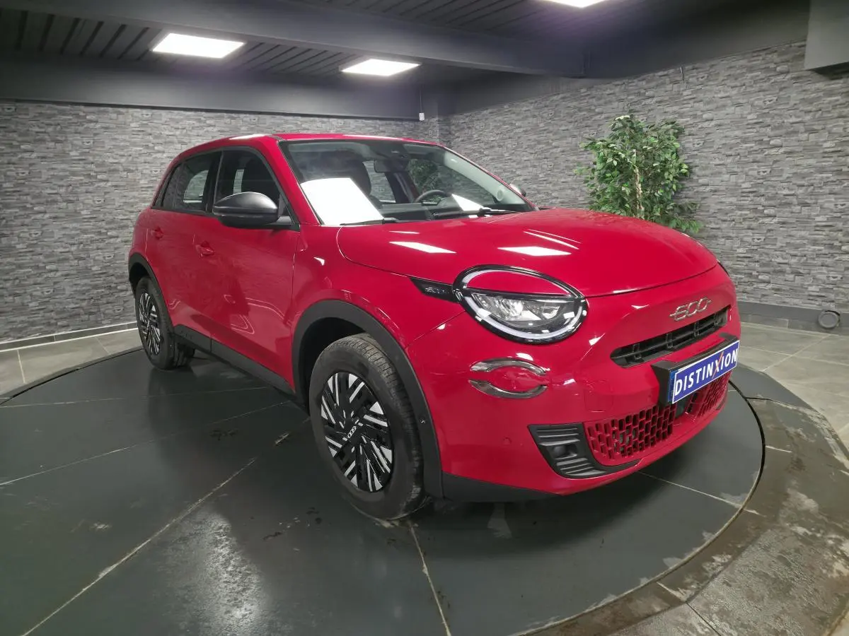 Vue 3/4 avant droite d'une FIAT 600 rouge 2024 avec jantes acier bicolores et coques de rétroviseurs noires.