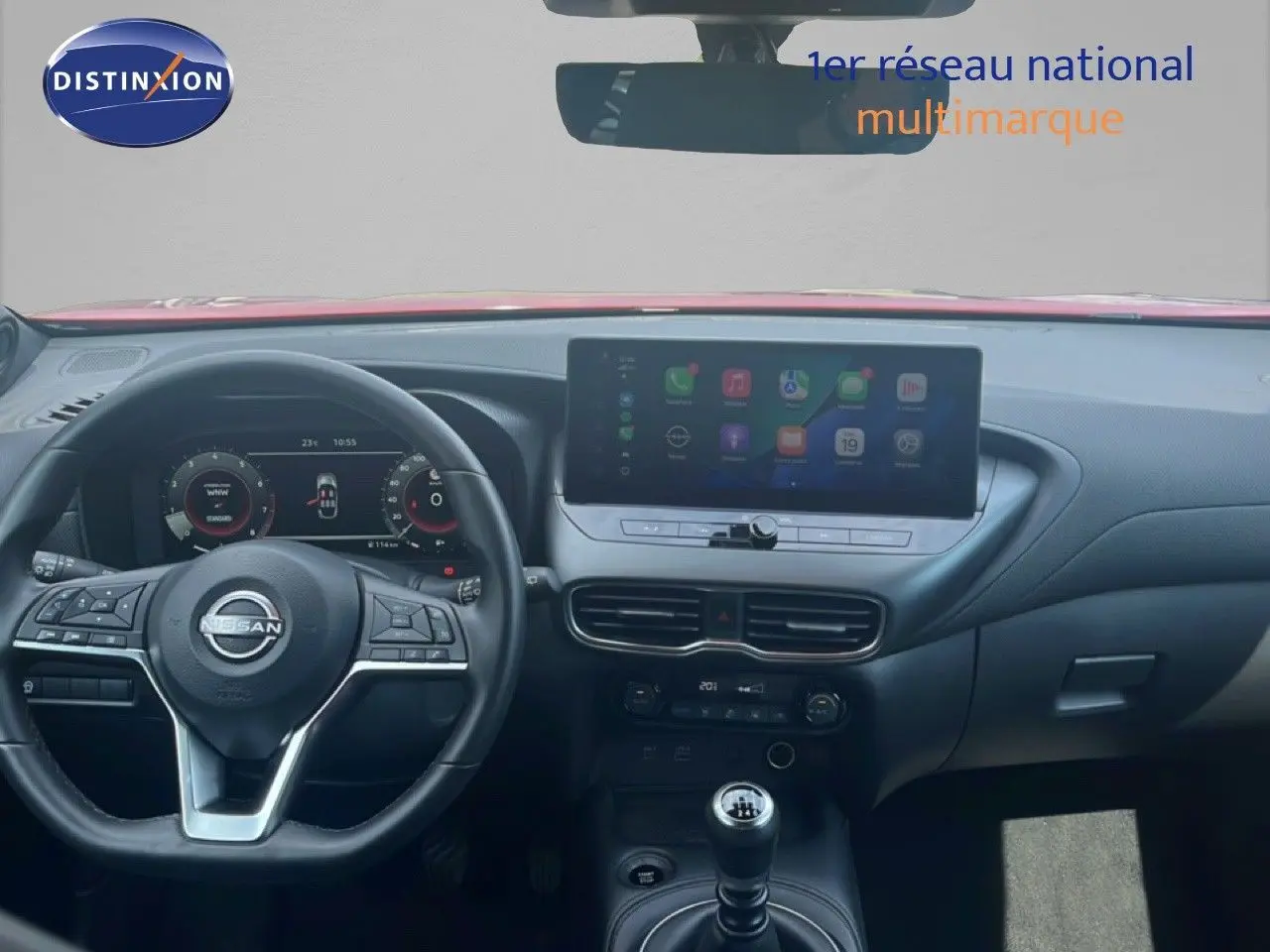 Vue intérieure du tableau de bord du Nissan Juke rouge Fuji Metal 2024, avec écran tactile et boîte manuelle.