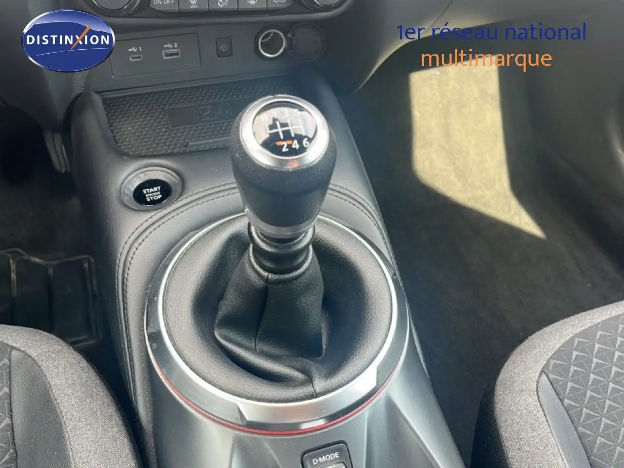 Le levier de vitesse manuel en gros plan dans l'habitacle noir du Nissan Juke rouge Fuji Metal 2024.