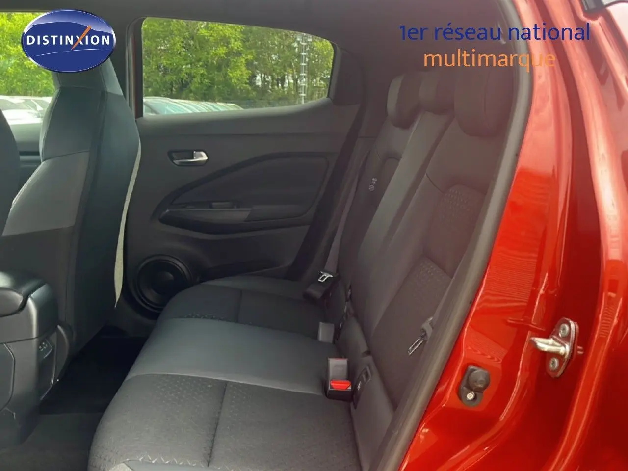 Vue intérieure côté droit sur les sièges arrière noirs du Nissan Juke 2024 rouge Fuji Metal avec porte ouverte.
