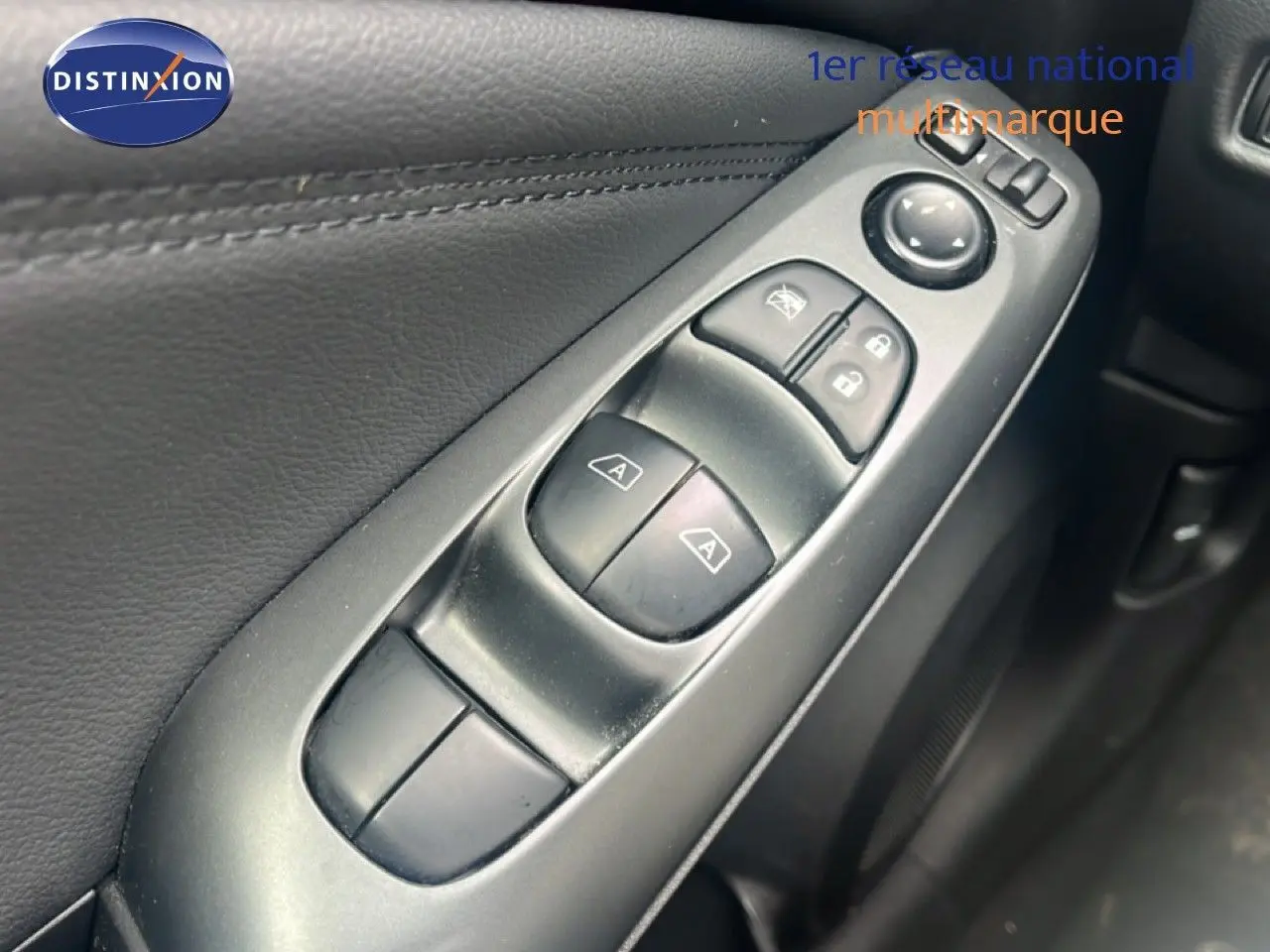 Gros plan sur les commandes de lève-vitres et rétroviseurs côté conducteur du Nissan Juke 2024 intérieur noir.