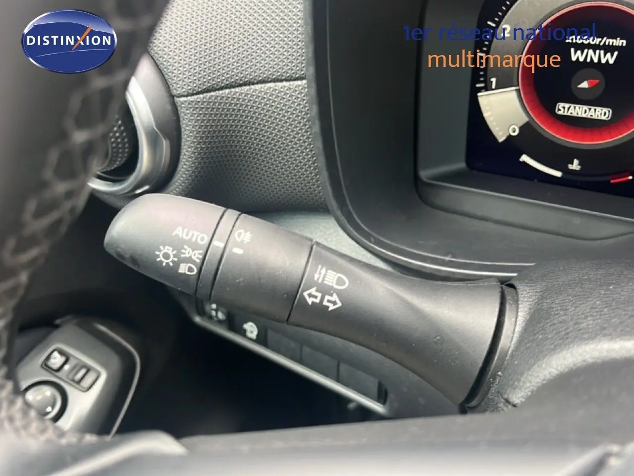 Gros plan sur la commande des feux et clignotants dans l’habitacle du Nissan Juke rouge Fuji Metal 2024.