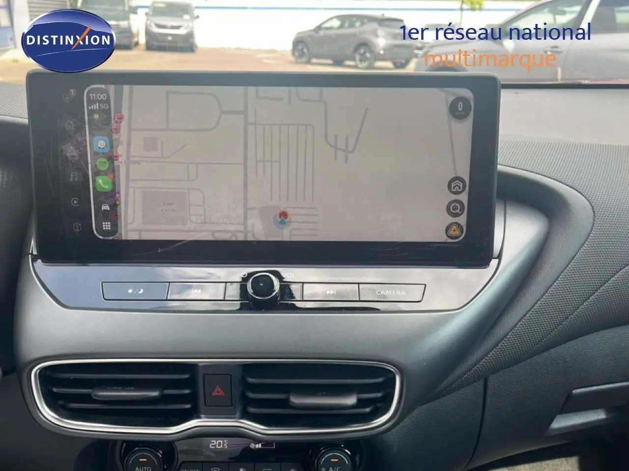 Vue rapprochée de la console centrale du Nissan Juke 2024 rouge Fuji Metal, avec écran tactile et commandes de climatisation.