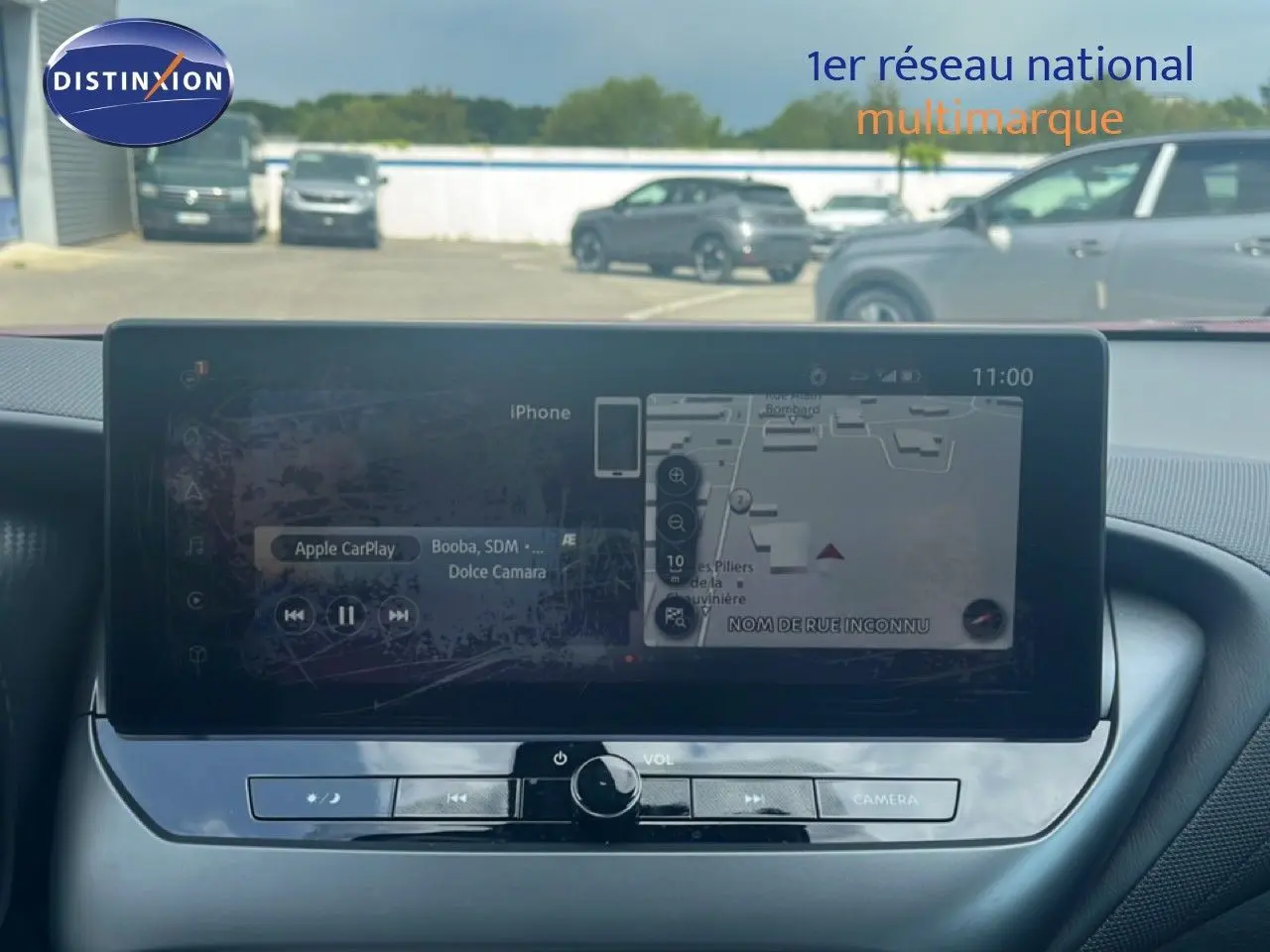 Écran tactile central du Nissan Juke rouge Fuji Metal 2024, affichant navigation et Apple CarPlay, vue intérieure frontale.