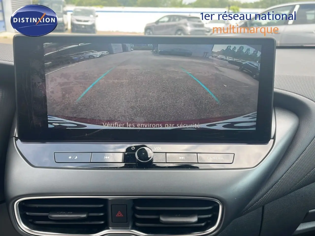 Vue intérieure centrée sur l'écran multimédia affichant la caméra de recul du Nissan Juke rouge Fuji Metal.