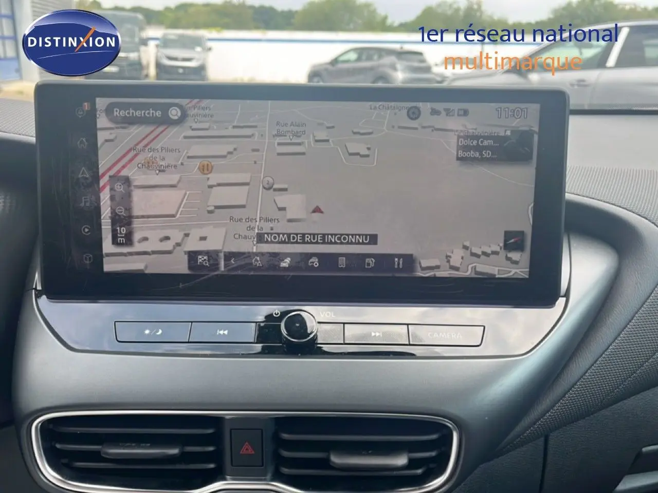 Écran tactile central du Nissan Juke 2024 rouge Fuji Metal, affichant la navigation GPS avec commandes intégrées.