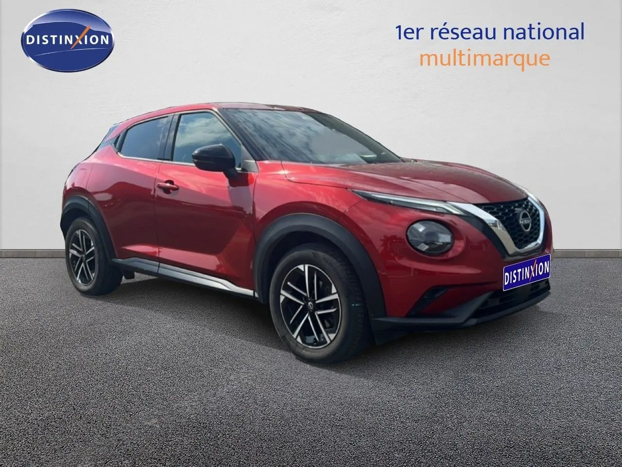 Nissan Juke rouge Fuji Metal en 3/4 avant droit, avec jantes alliage et calandre chromée distinctive.