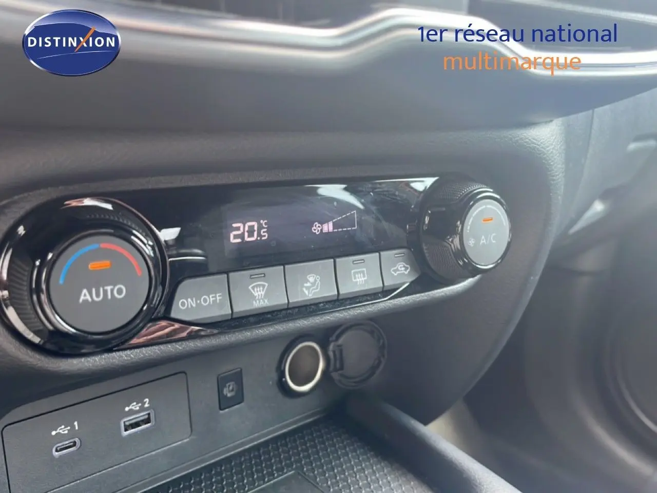Détail de la console centrale du Nissan Juke rouge Fuji Metal 2024, montrant les commandes de climatisation et ports USB.