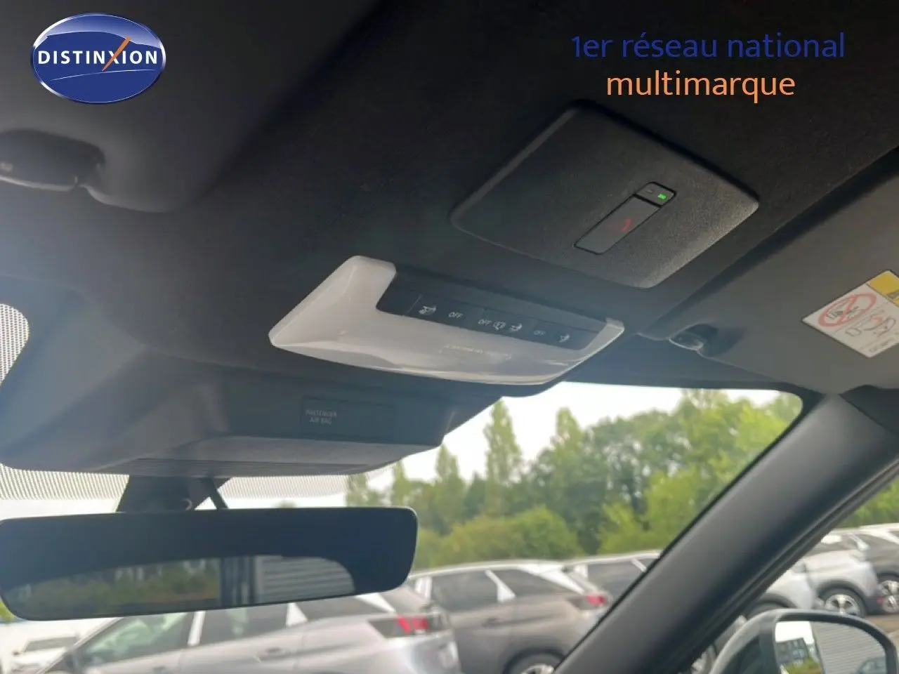 Vue intérieure du toit et rétroviseur d’un Nissan Juke 2024 rouge Fuji Metal, avec commandes au plafond visibles.