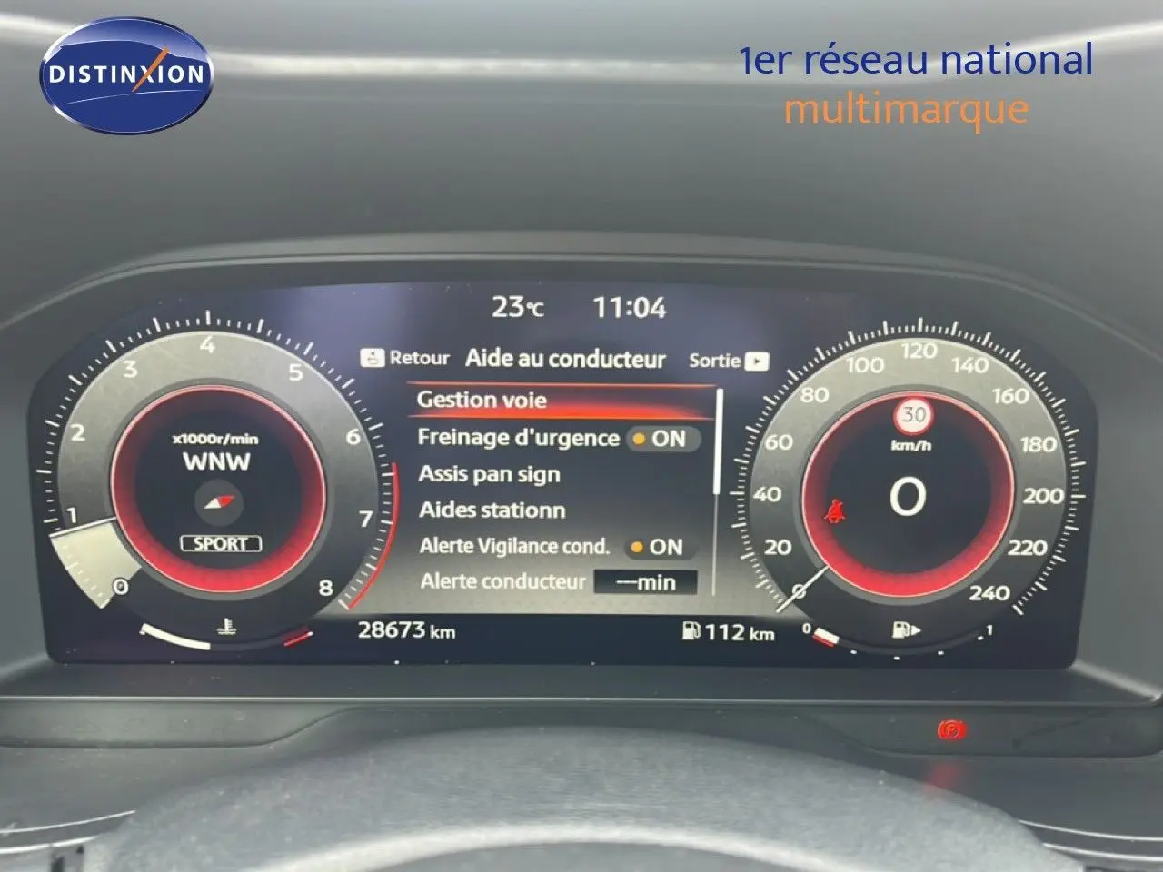 Tableau de bord numérique du Nissan Juke rouge Fuji, affichant les aides à la conduite et compteurs à 0 km/h.