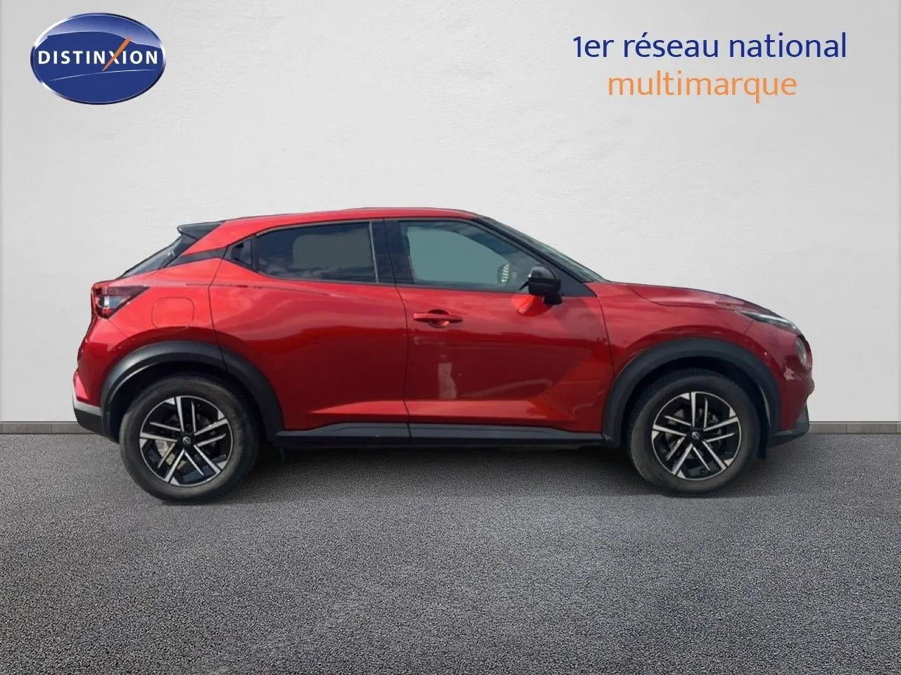 Profil côté gauche du Nissan Juke 2024 rouge Fuji Metal avec jantes alliage noires et toit noir contrasté.