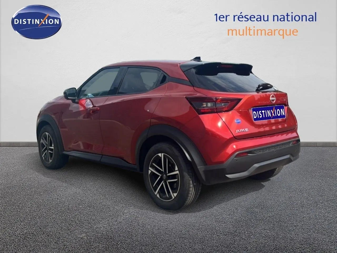 Vue 3/4 arrière droite d'un Nissan Juke 2024 rouge Fuji Metal avec jantes alliage et toit noir.
