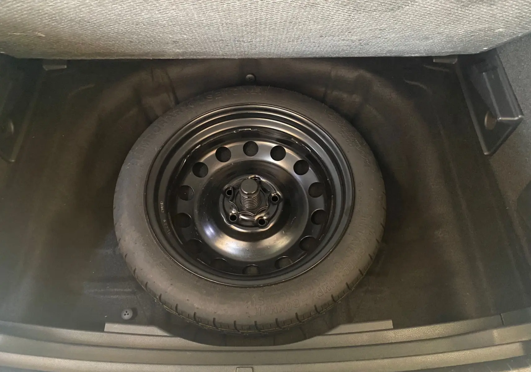 Roue de secours noire en acier logée dans le coffre d'un SEAT Ateca Urban 2019 diesel 1.6l TDI.