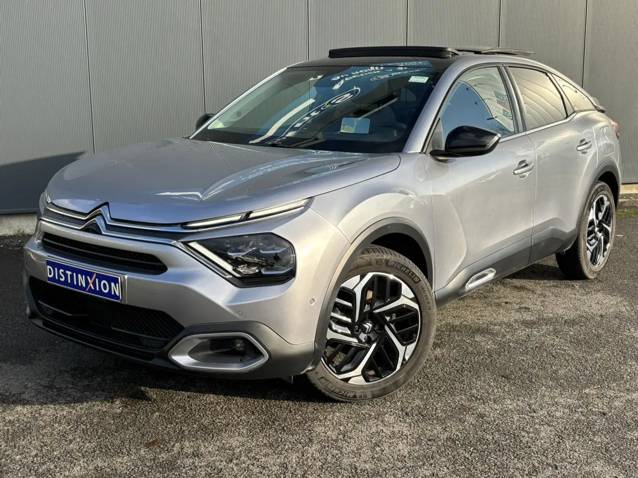 Citroën C4 PureTech 130 gris Artense en 3/4 avant droit, avec jantes alliage et toit ouvrant électrique.