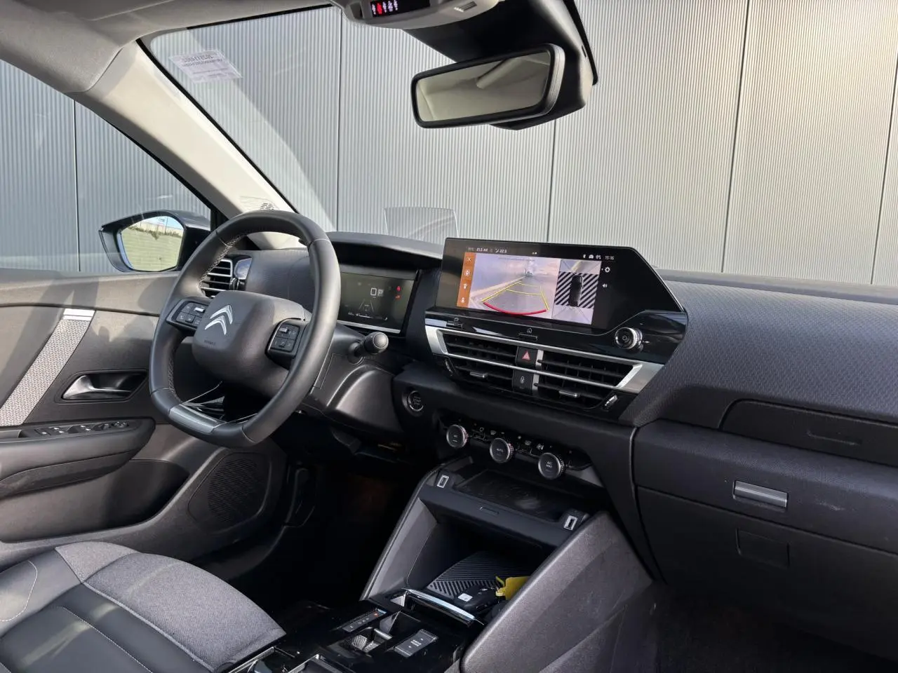 Vue intérieure avant droite de la Citroën C4 2024, tableau de bord noir avec écran tactile affichant la caméra de recul.