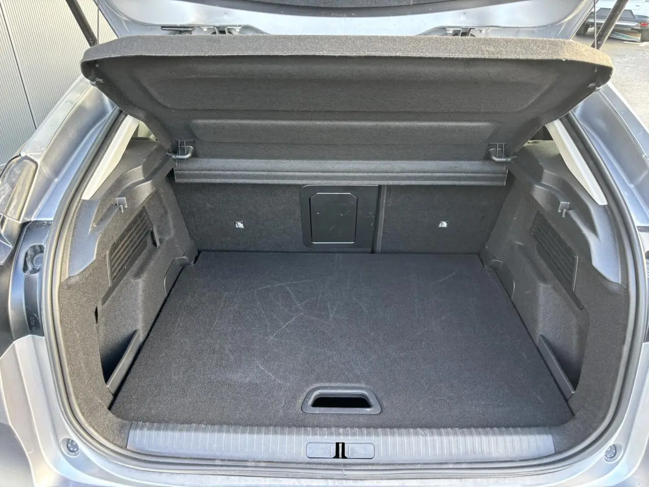 Coffre ouvert vu de l'arrière d'une Citroën C4 2024 gris Artense, espace de chargement propre et volumineux.