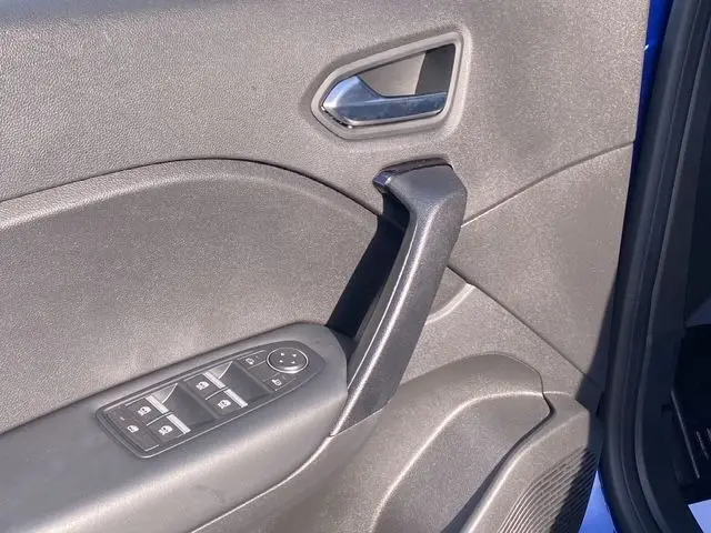 Vue rapprochée de la porte avant gauche du Renault Captur bleuiron, avec commandes de vitres et poignée noire.