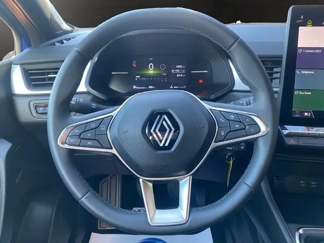 Vue rapprochée du volant noir en tissu du Renault Captur 2024 avec tableau de bord numérique et écran tactile à droite.
