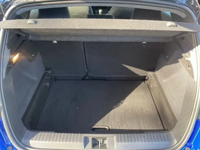 Coffre ouvert vu de l'arrière d'un Renault Captur BleuIron avec intérieur noir et cache-bagages en place.