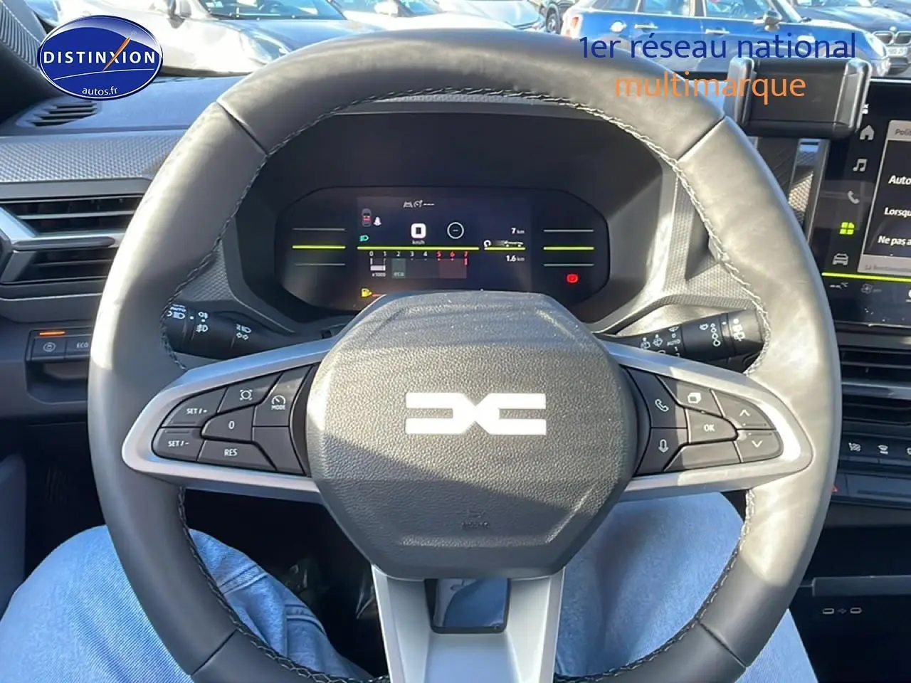 Vue intérieure centrée sur le volant multifonction noir du Dacia Duster 2026 avec tableau de bord numérique en arrière-plan.