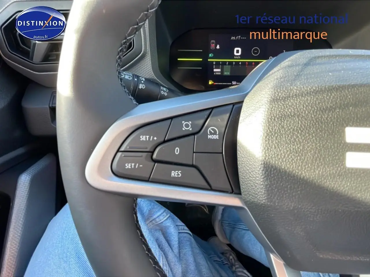 Gros plan sur les commandes à gauche du volant du Dacia Duster noir, avec affichage numérique du tableau de bord en arrière-plan.