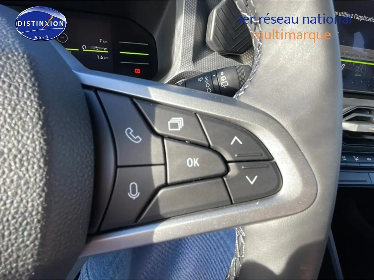 Gros plan sur les commandes multifonctions du volant du Dacia Duster noir, avec écran tactile et tableau de bord en arrière-plan.