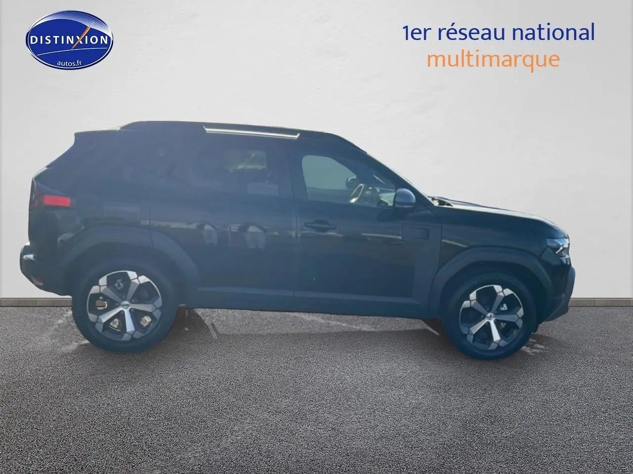 Profil latéral gauche d’un Dacia Duster noir 2026 avec jantes alliage et barres de toit visibles.