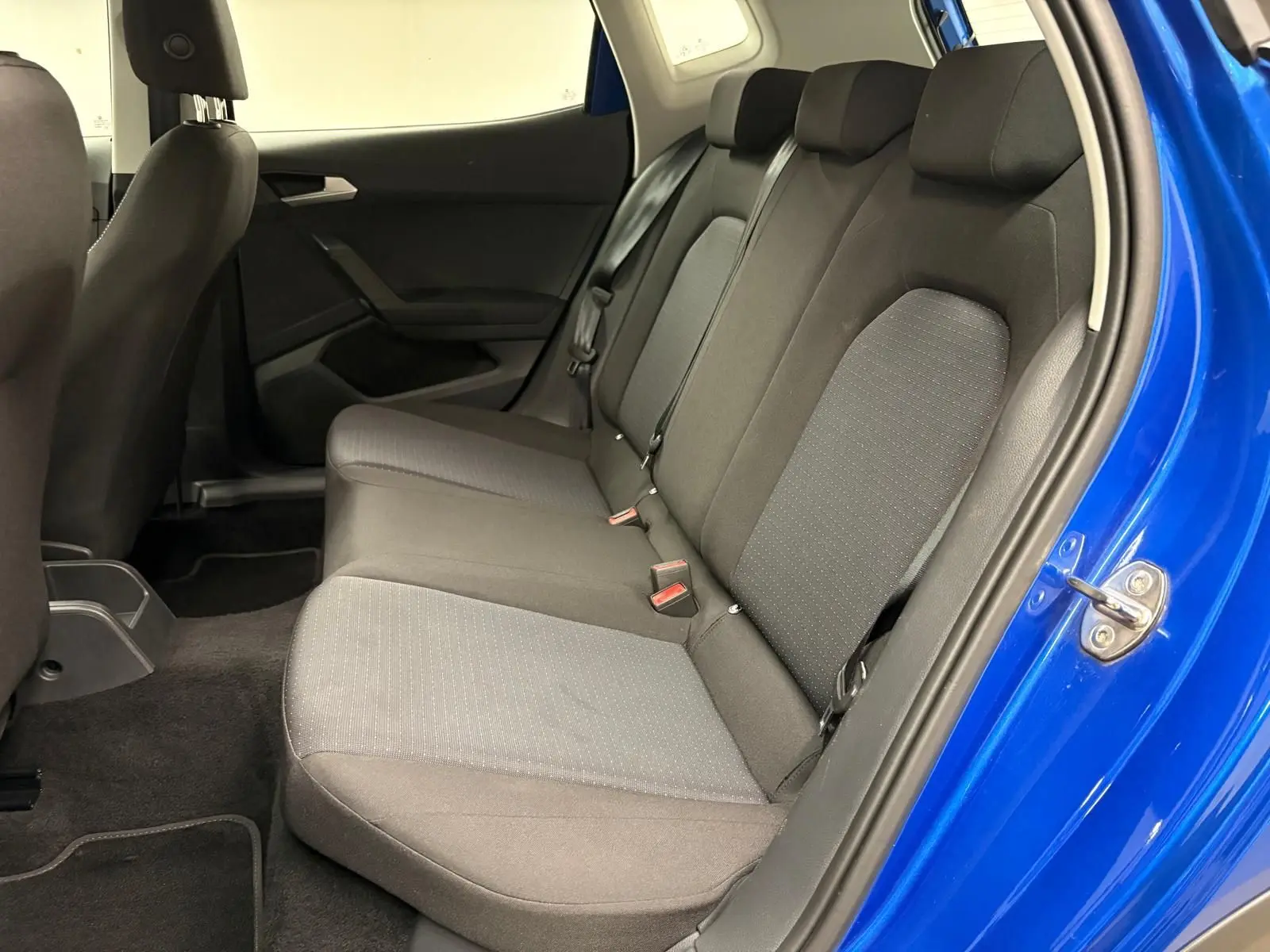 Vue intérieure côté gauche des sièges arrière noirs d’un SEAT Arona 2025 en Bleu Saphir avec porte ouverte.