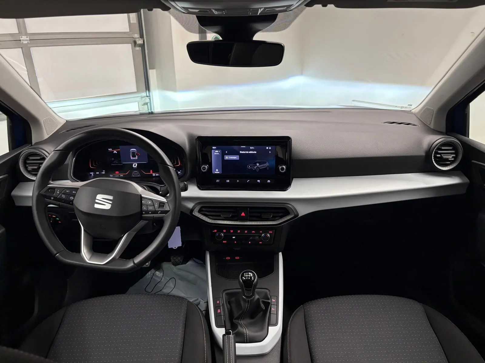 Vue intérieure frontale du tableau de bord et volant de la SEAT Arona 2025 avec boîte manuelle et écran tactile central.