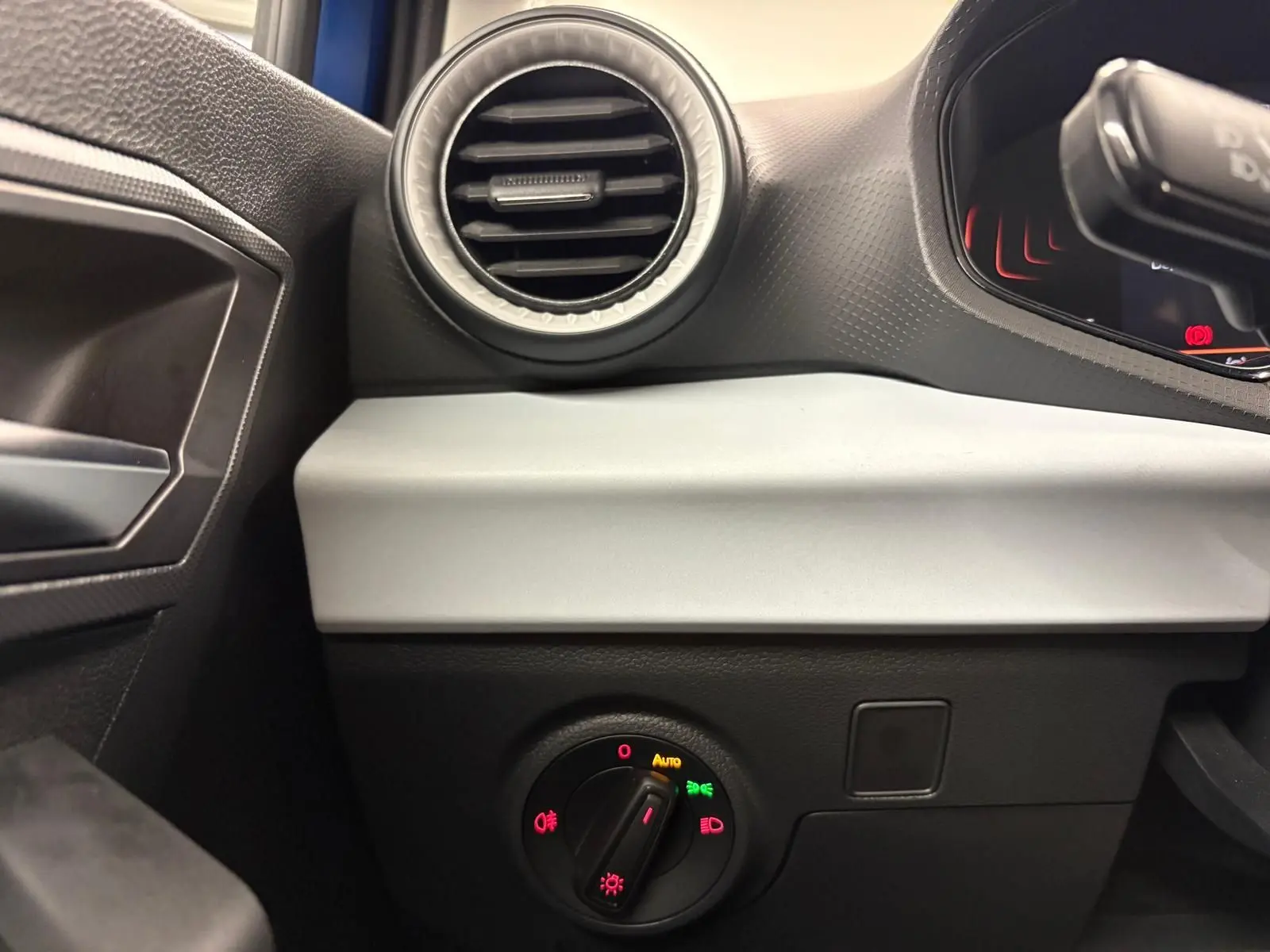 Détail intérieur côté gauche du tableau de bord du SEAT Arona 2025, avec commande des feux et aérateur rond.
