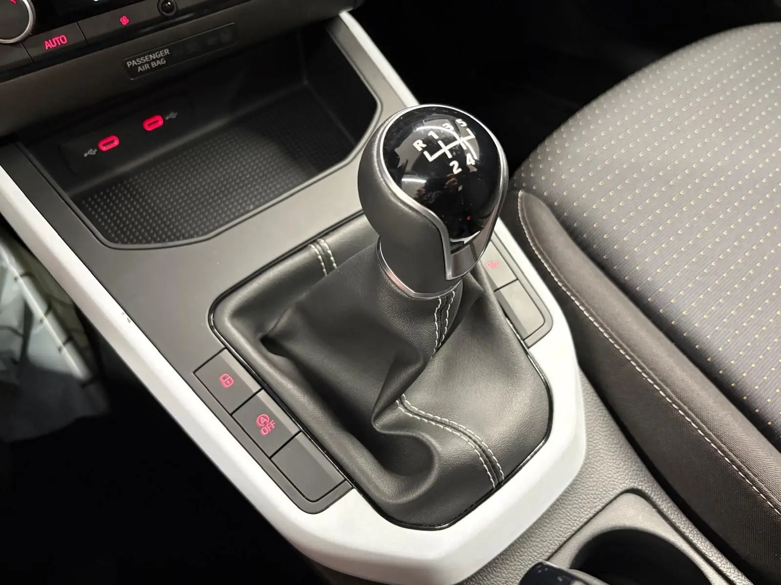 Gros plan sur la commande de la boîte manuelle noire avec coutures blanches dans l’habitacle du SEAT Arona 2025.