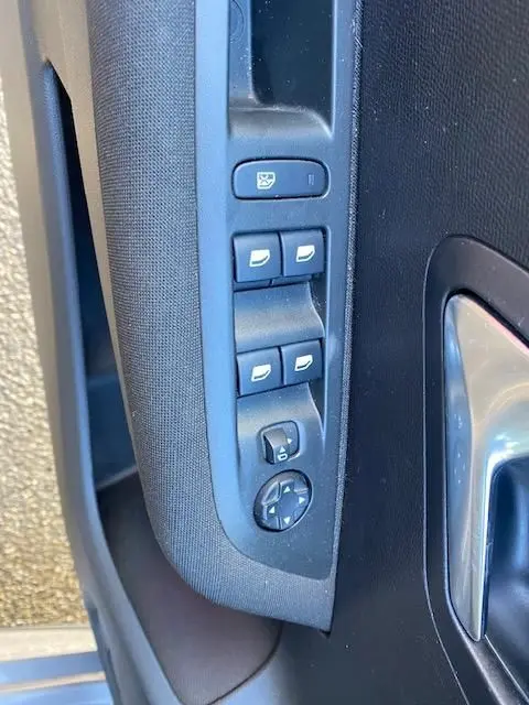 Gros plan sur les commandes de lève-vitres et rétroviseurs sur la porte côté gauche d'une Peugeot 208 gris platinium.