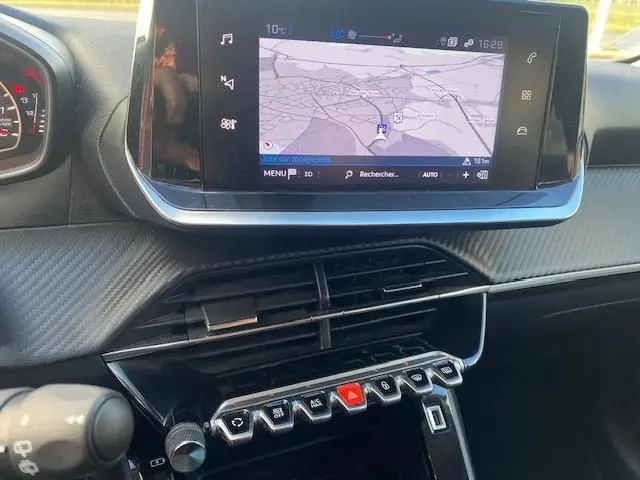 Vue intérieure du tableau de bord de la Peugeot 208 gris platinium, avec écran tactile affichant la navigation et commandes centrales.