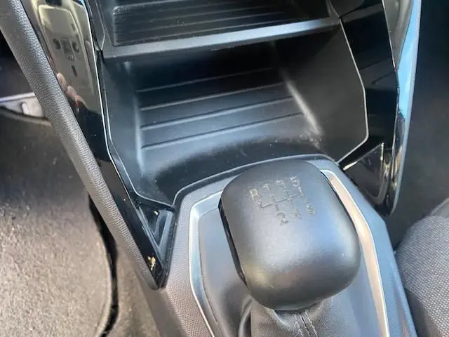 Gros plan sur le levier de vitesses manuel noir de la Peugeot 208 gris platinium, avec console centrale en plastique noir brillant.