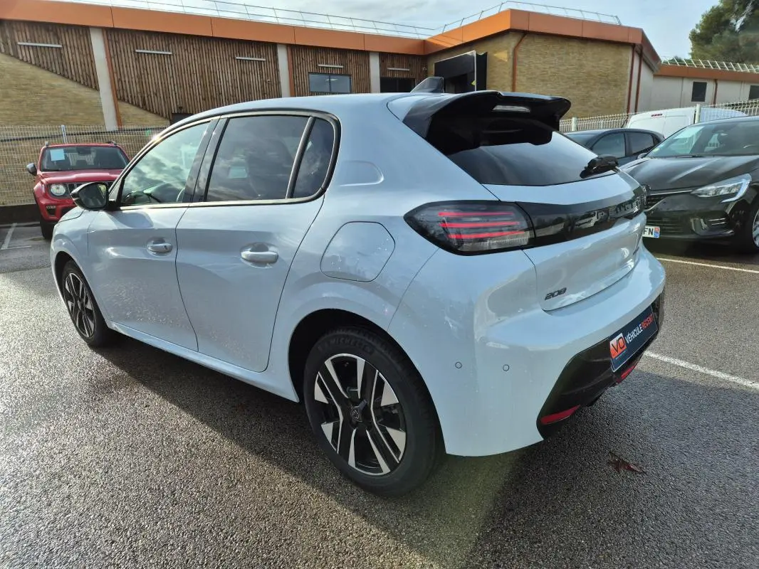Vue 3/4 arrière droite d’une Peugeot 208 Hybrid 110 blanche avec jantes alliage 16 pouces et feux arrière LED noirs.