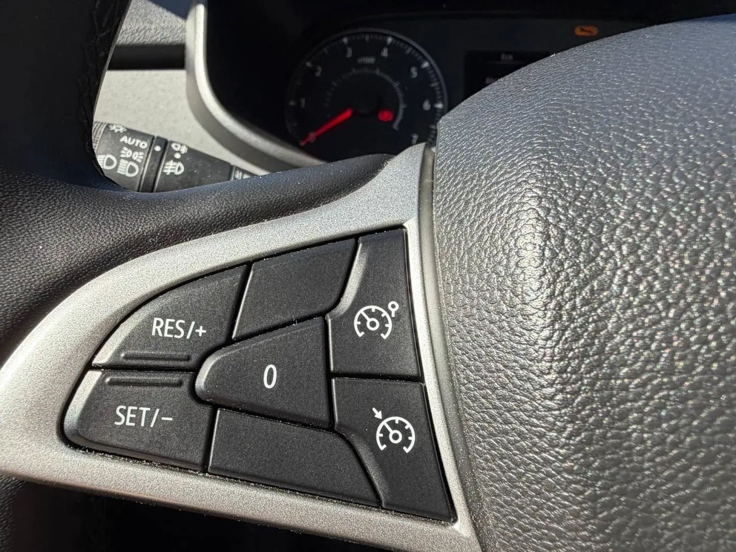 Gros plan sur les commandes de régulateur de vitesse au volant noir du Dacia Sandero 2025.