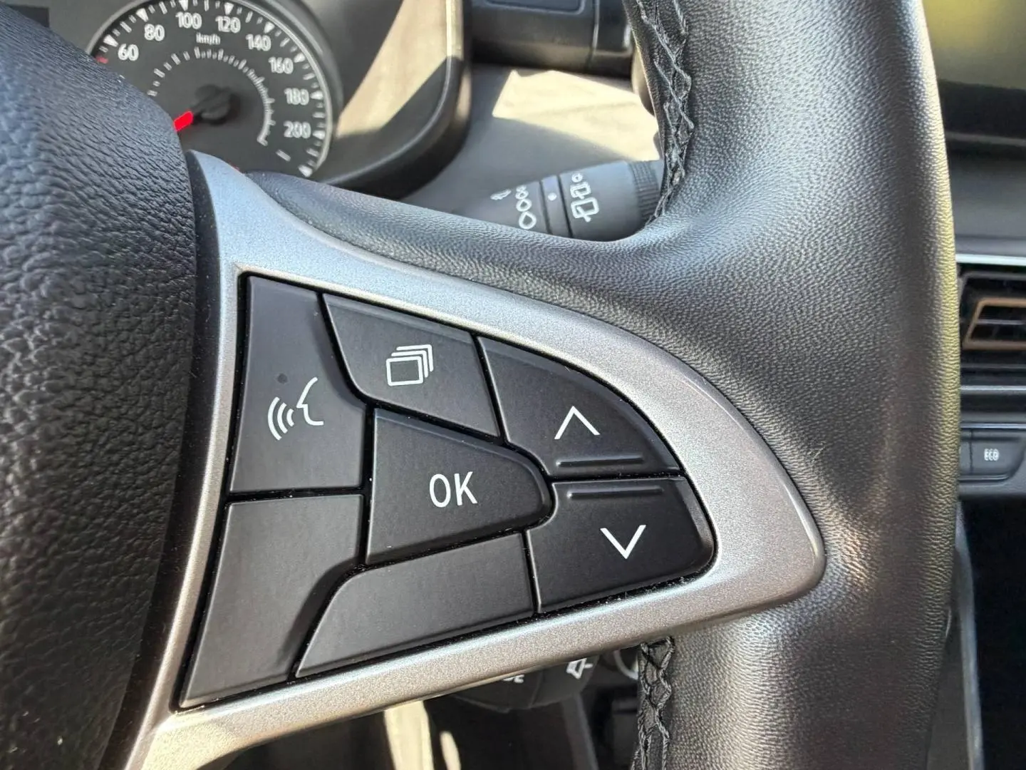 Gros plan sur les commandes multifonctions à gauche du volant en cuir noir du Dacia Sandero 2025.