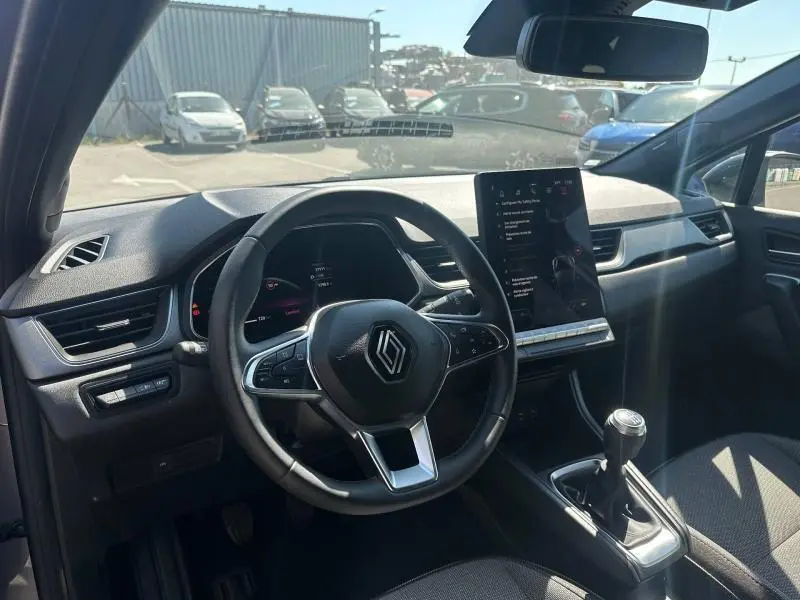 Vue intérieure avant du Renault Captur 1.0 Eco-G 100ch Techno 2025, volant multifonction et écran tactile vertical.