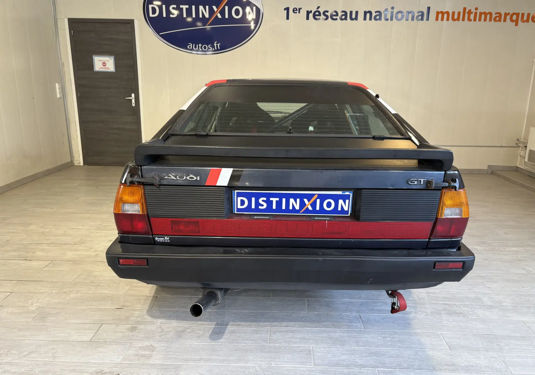 Gros plan intérieur sur l'arceau de sécurité avec autocollant FFSA et extincteur rouge dans un Audi Coupé GT noir de 1983.
