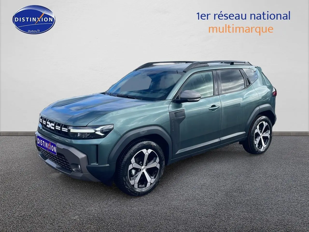 Vue 3/4 avant du Dacia Duster 2026 vert cèdre avec jantes alliage et barres de toit noires.
