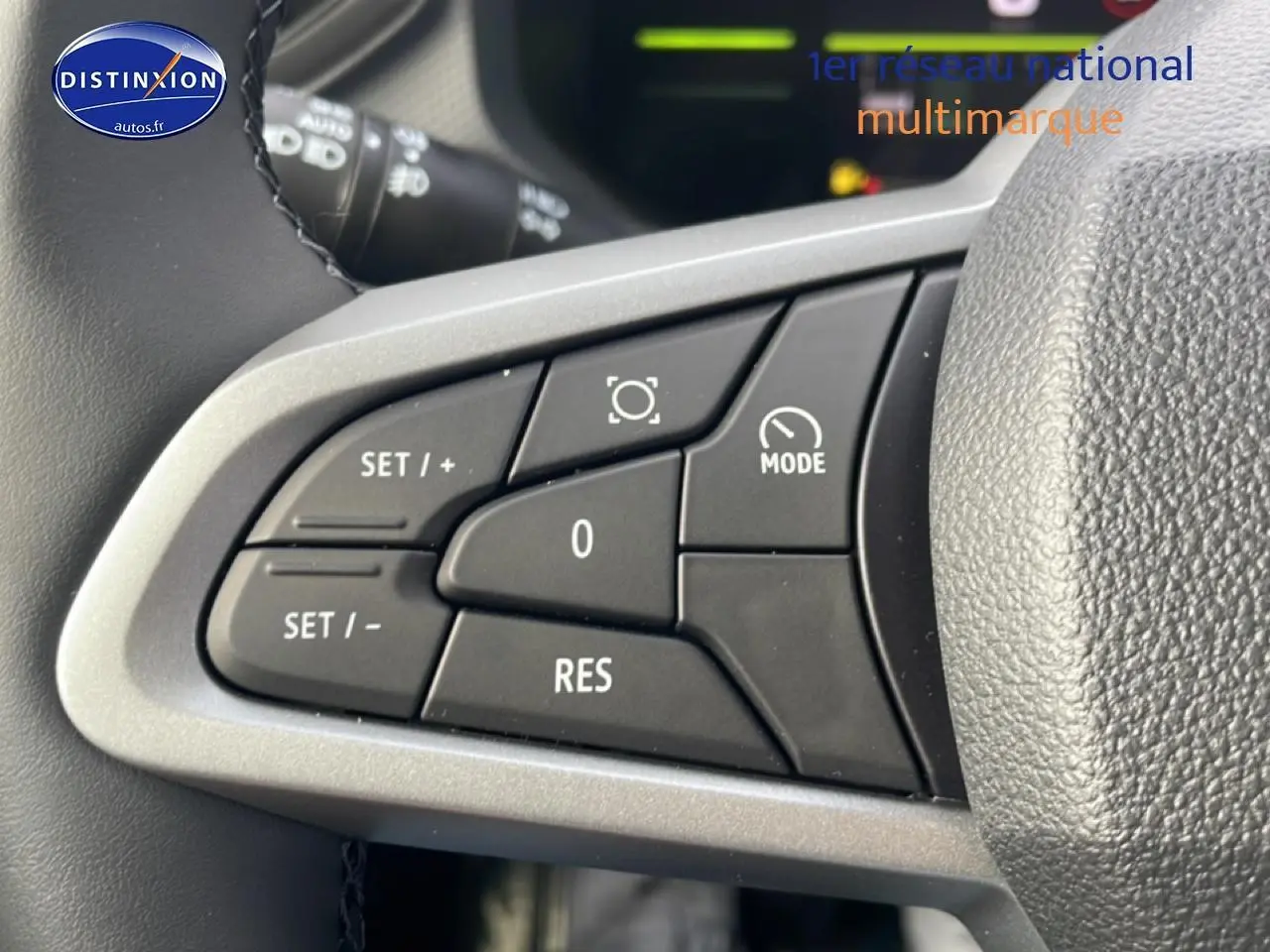 Gros plan sur les commandes multifonctions au volant du Dacia Duster 2026, boutons noirs sur fond gris.