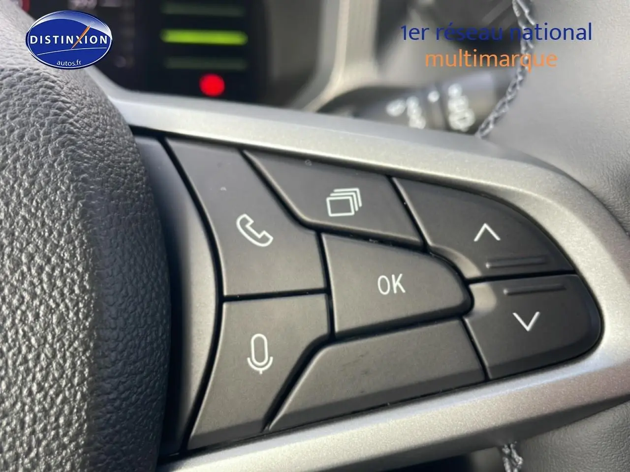 Gros plan sur les commandes multifonctions noires du volant du Dacia Duster 1.2 mild hybrid 2026, finition gris argenté.