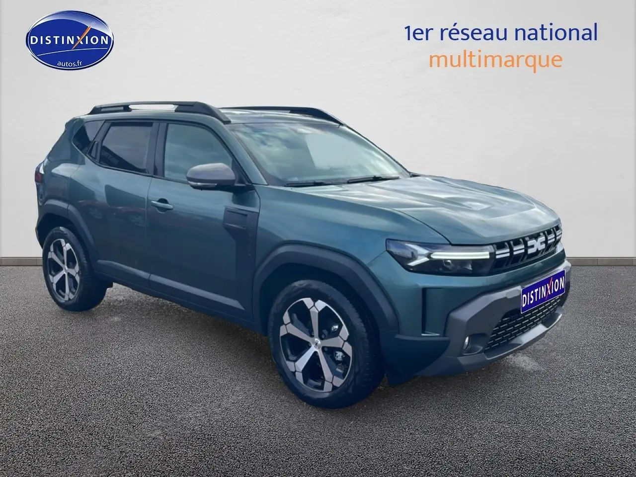 SUV Dacia Duster vert cèdre en vue 3/4 avant droit, avec jantes alliage et barres de toit noires.