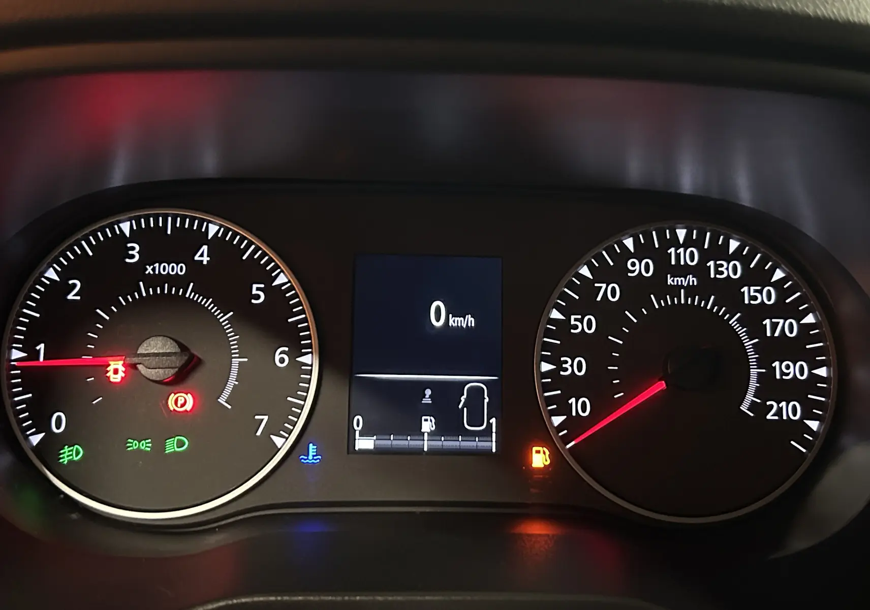 Tableau de bord du Dacia Duster blanc, affichage digital au centre avec vitesse à 0 km/h et voyants allumés.