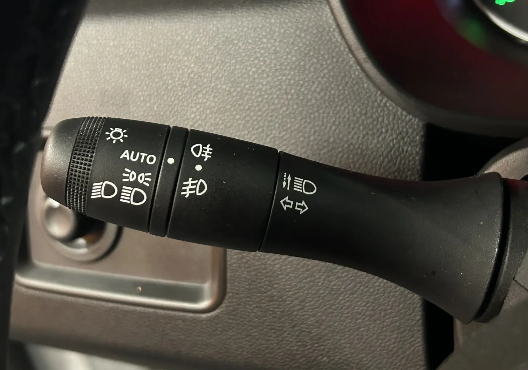 Gros plan sur la manette de commande des phares et clignotants du Dacia Duster blanc, vue intérieure côté gauche.