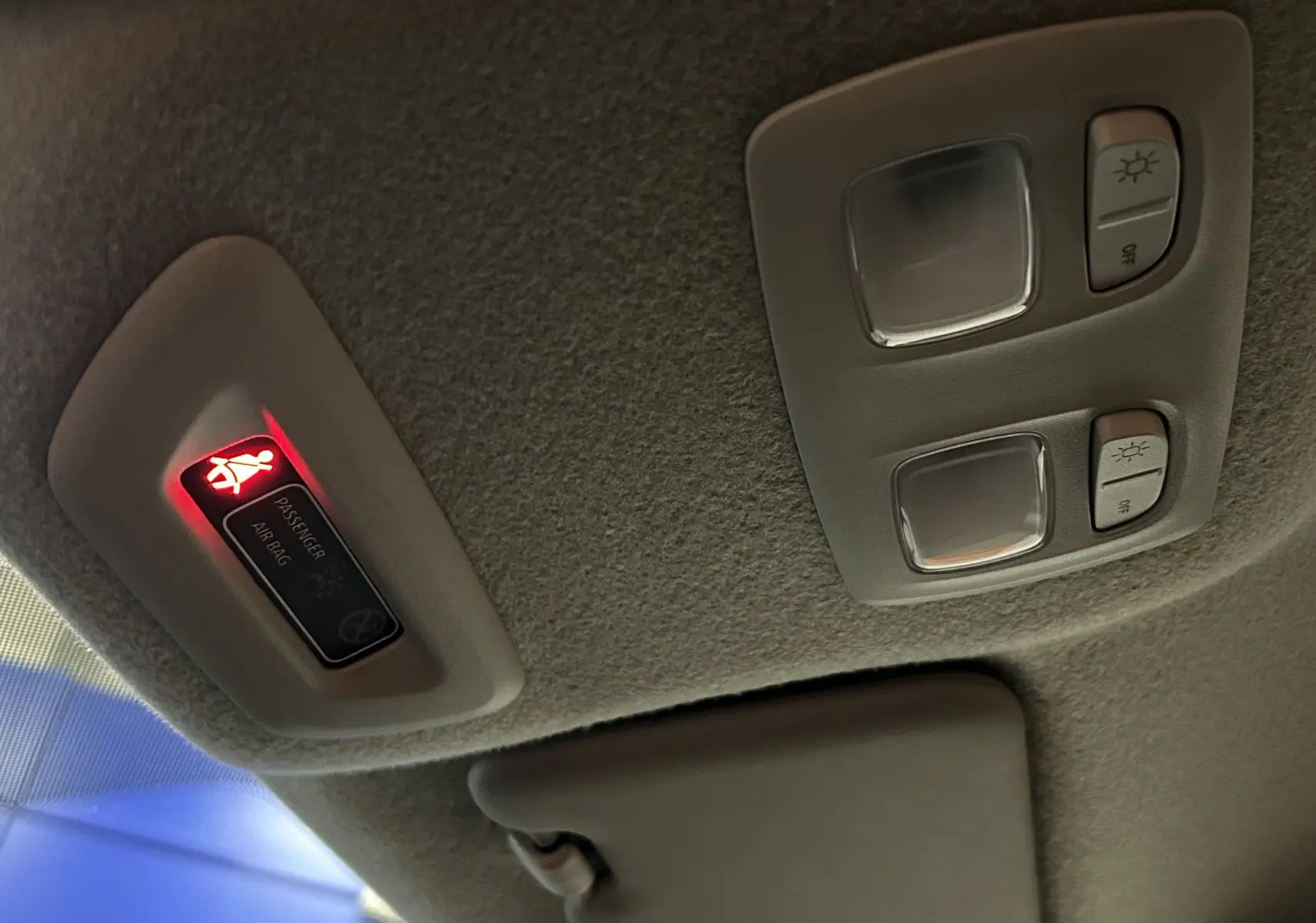 Vue intérieure du plafonnier avec éclairages et témoin airbag passager allumé dans un Dacia Duster blanc 2025.