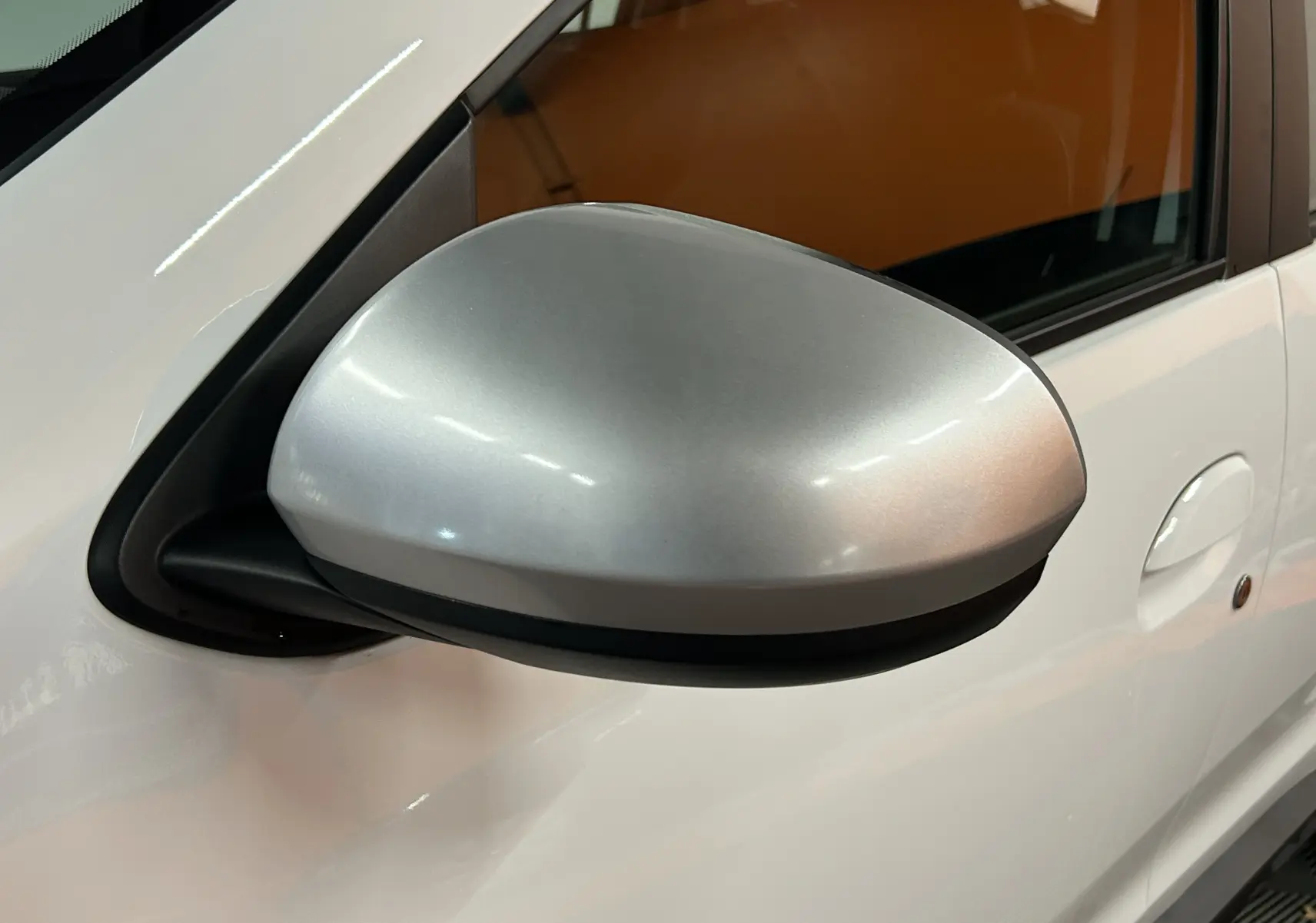 Rétroviseur extérieur côté gauche argent sur Dacia Duster blanc, vue rapprochée du côté conducteur.