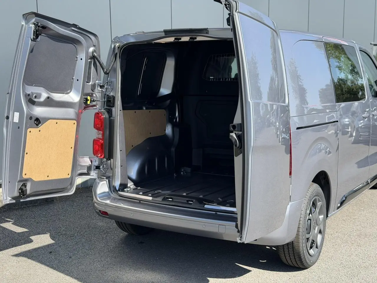 Vue arrière droite d'un Citroën Jumpy gris Artense avec portes battantes ouvertes dévoilant l'espace de chargement vide.
