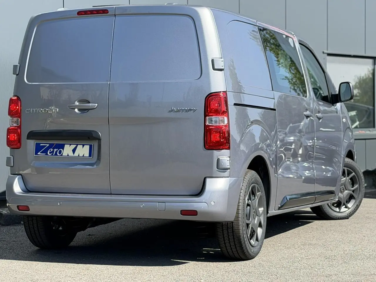 Vue 3/4 arrière droite d'un Citroën Jumpy gris Artense avec portes arrière battantes et jantes noires.
